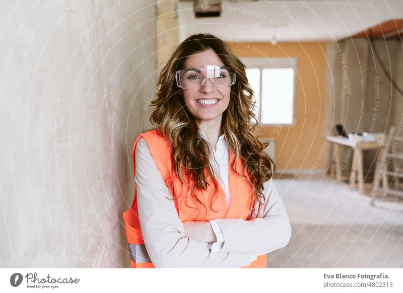 smiling professional confident architect woman in construction site. Home renovation portrait blueprints workspace protective helmet protective jacket
