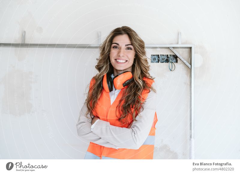 smiling professional confident architect woman in construction site. Home renovation portrait blueprints workspace protective helmet protective jacket