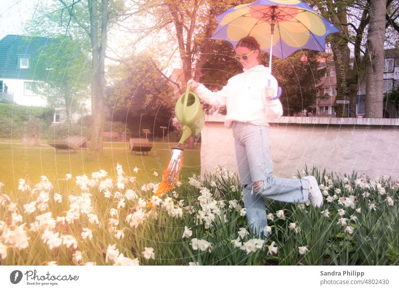 Girl with parasol standing in flower bed watering the flowers Spring Watering can Garden Gardening Cast Exterior shot Plant Gardener Flower Nature Colour photo