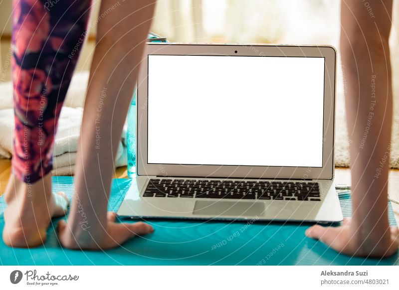 Woman using laptop and working out on yoga mat at home. Distant work. Healthy lifestyle and social media concept. White empty screen. Healthy lifestyle and social media. Close-up white empty screen.
