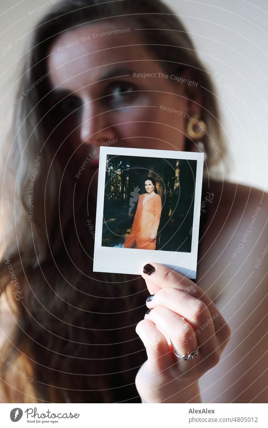 Young woman holding Polaroid picture of herself to camera Woman pretty Feminine feminine Slim Identity Analog analog image film photography Authentic Esthetic