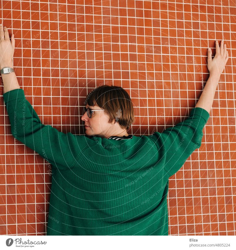 [hansa BER 2022] Woman with green sweater stretches her hands on a red tiled wall Wall (building) Red Outstretched Human being Arm Contrast Adults Eyeglasses