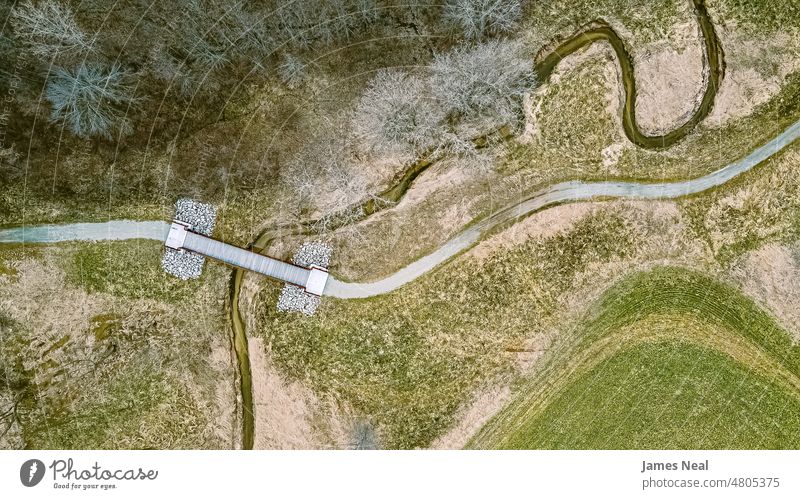 Aerial view in springtime with a trail and spiraling river grass natural color bridge peaceful nature water day beauty background trees creek wild united states