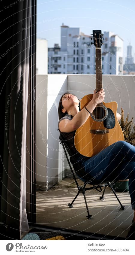 Asian woman with guitar on balcony Guitar Balcony guitarists outdoors sunshine asian hobby thinking hobbies Leisure and hobbies Sunlight Sunbeam relax relaxing