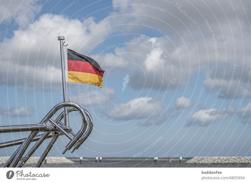 the stainless steel railing on the stern of a sailer with Germany flag in the harbor with view on Barther Bodden, blue sky with white clouds Stern Railing