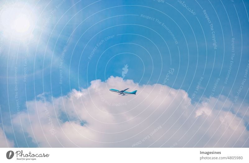 Airplane flying high, blue sky and clouds with sun and sun rays. Commercial airplane flying towards clouds in blue sky. Silhouette of airplane flying in the clouds. from below