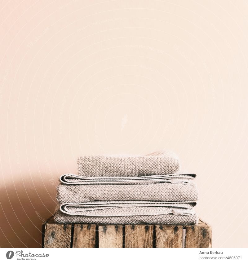 Folded towels on wooden box in front of a bright wall Towels pooled Housekeeping Arrangement Living or residing fresh laundry tidy Photos of everyday life