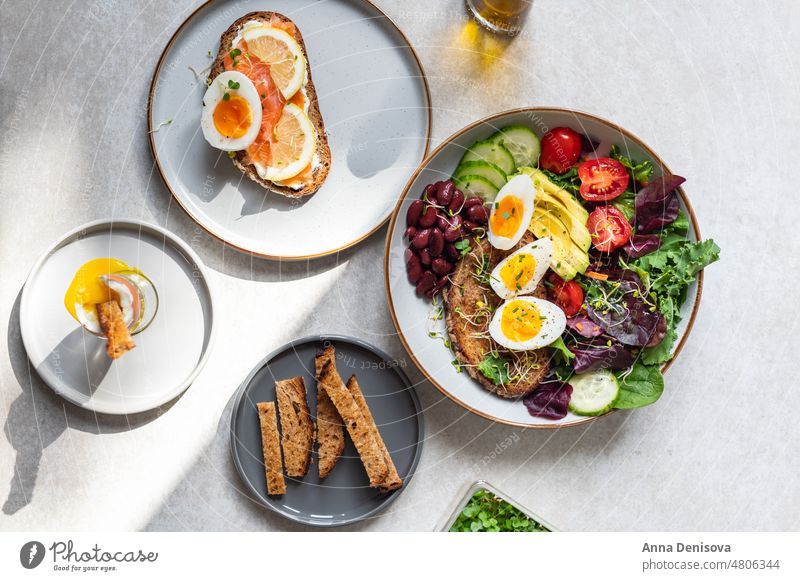 Toast with salmon and medium boiled eggs soft-boiled diet bread yolk yellow toast green salad leaves avocado cherry tomatoes cucumber red beans micro greens