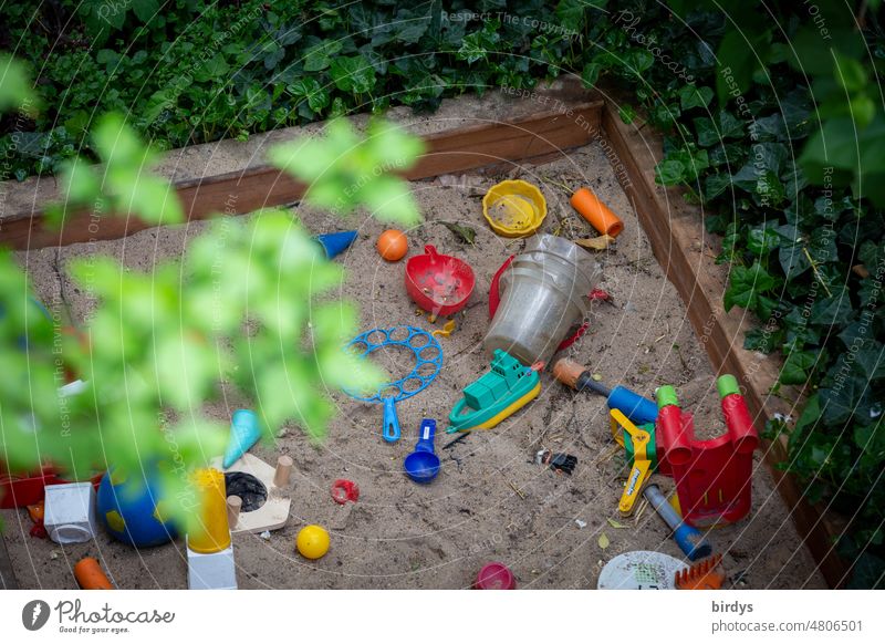 A sandbox surrounded by green plants with children - toys in the garden from oblique bird's eye view Sandpit Infancy Toys Sand toys Garden Children's game