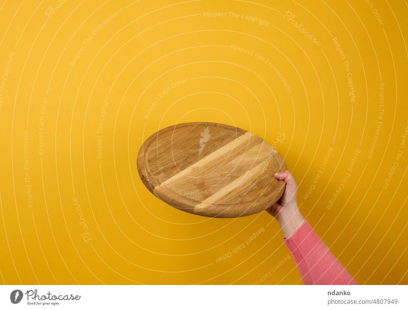 woman holding empty round wooden pizza board in hand, body part  ona  yellow background brown caucasian chef chop circle cook cutting board dish domestic