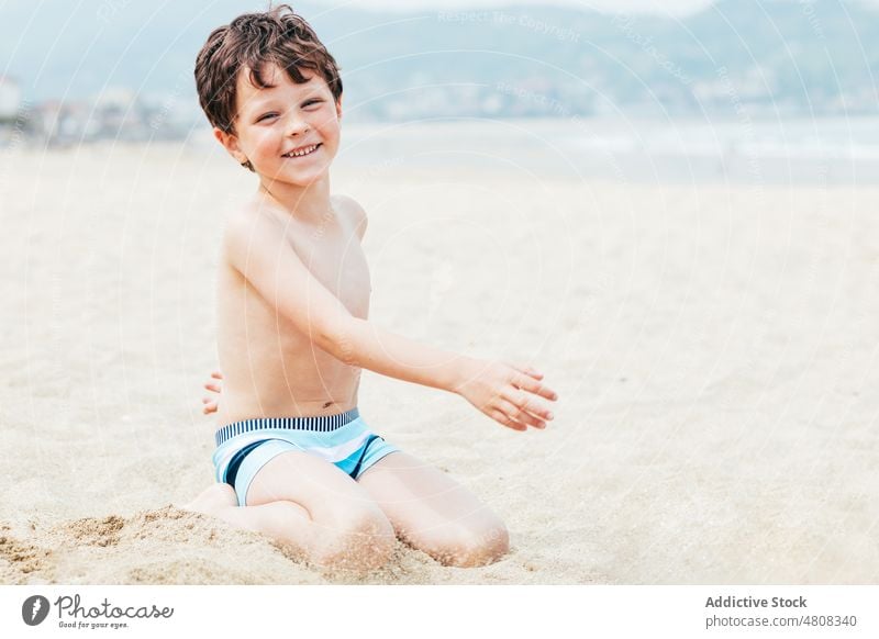 Boy looking at camera on beach boy rest weekend summer vacation smile portrait resort child daytime cute kid childhood shore relax adorable happy cheerful coast
