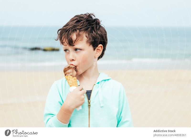 Boy eating chocolate ice cream at the beach boy lick smile summer weekend portrait sweet kid child dessert cute delicious yummy adorable childhood seaside water