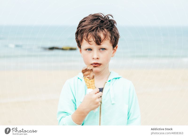 Boy eating chocolate ice cream at the beach boy lick smile summer weekend portrait sweet kid child dessert cute delicious yummy adorable childhood seaside water