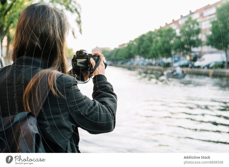 Female photographer taking pictures of river from embankment in city woman take photo photo camera canal building sightseeing traveler vacation architecture