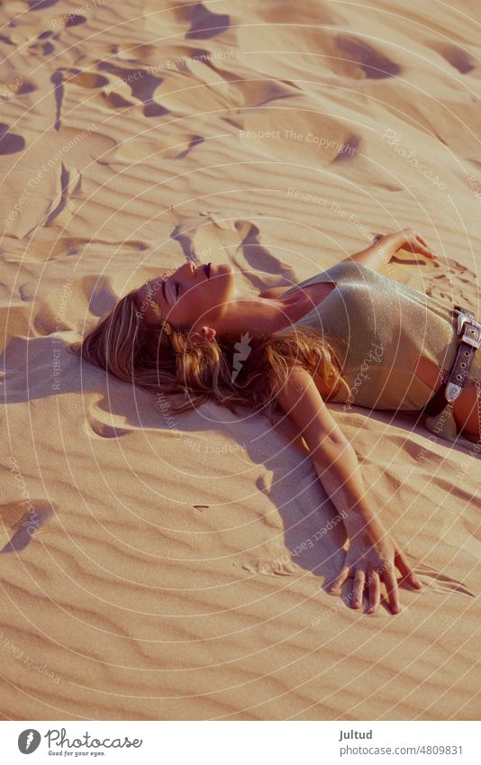 young model poses on the golden sand of the dunes by the sea fashion fashionable beach desert woman lady daylight Sun exotic vogue caucasian caucasian ethnicity
