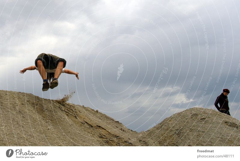somersault Man Woman Jump Action Gray Bad weather Mining Sand Desert Rain Clouds Flying Movement Dynamics Construction