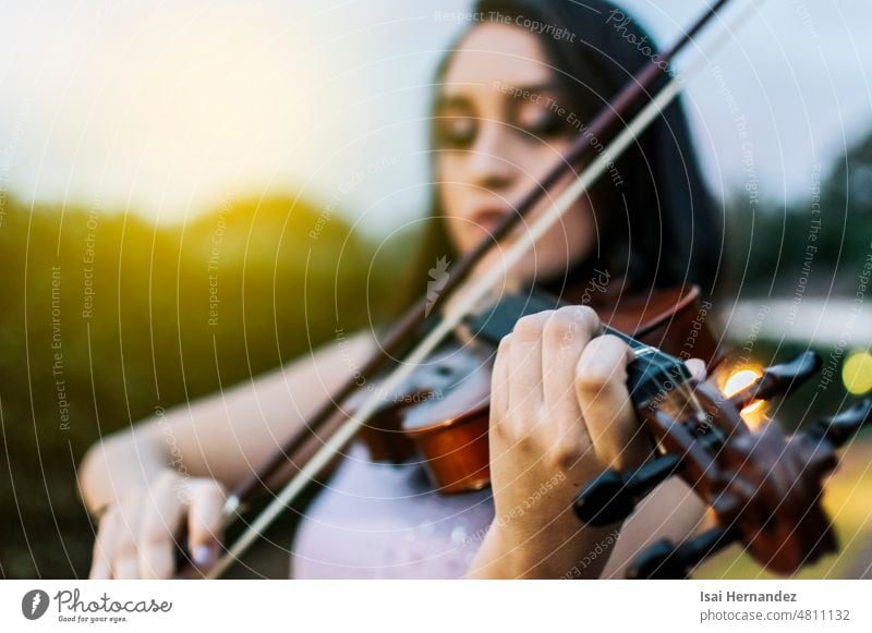 Close up of hands of a woman playing violin outdoors, A girl with her violin playing a melody outdoors, face of a woman playing violin, Portrait of a girl playing violin