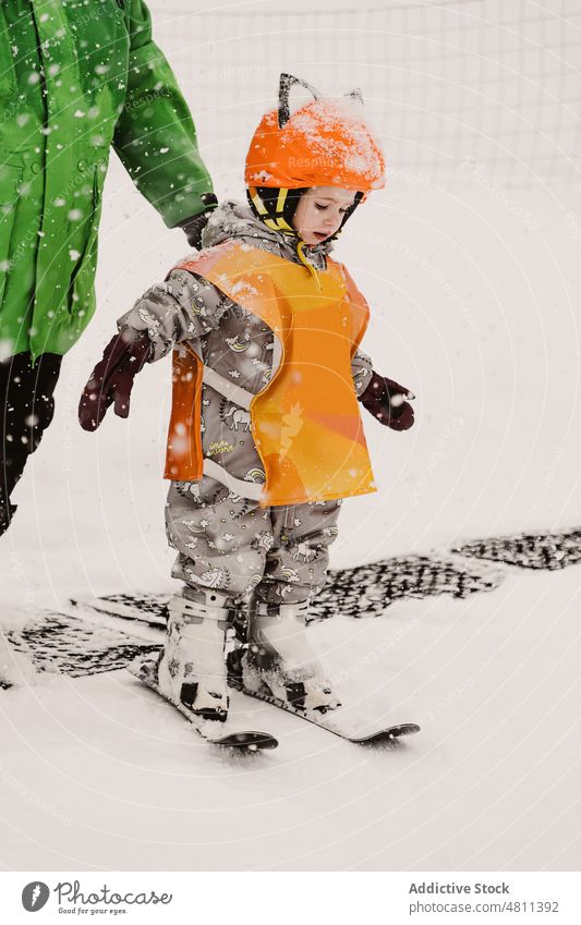 Adorable child balancing on slope during skiing lesson practice snow balance activity learn mountain winter training instructor sport kid warm clothes helmet