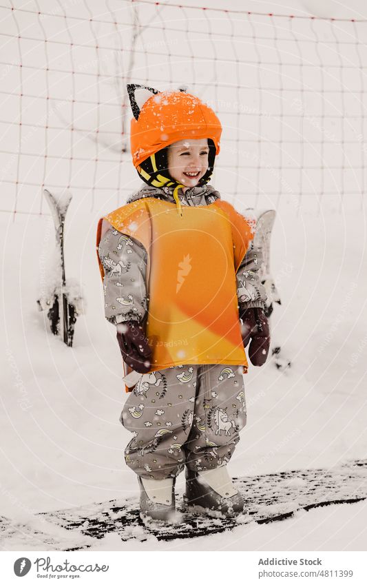 Happy child in winter overalls and helmet smiling in snowy terrain smile skier ski resort activity cheerful kid childhood holiday hobby happy outerwear protect