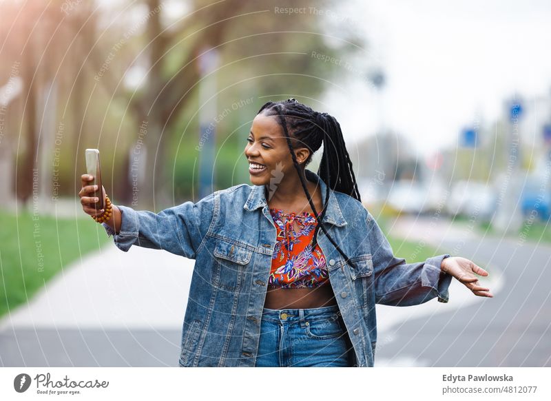 Young woman using her smartphone in the city cool carefree confident day millennials dreadlocks enjoy authentic positive real people joyful toothy smile