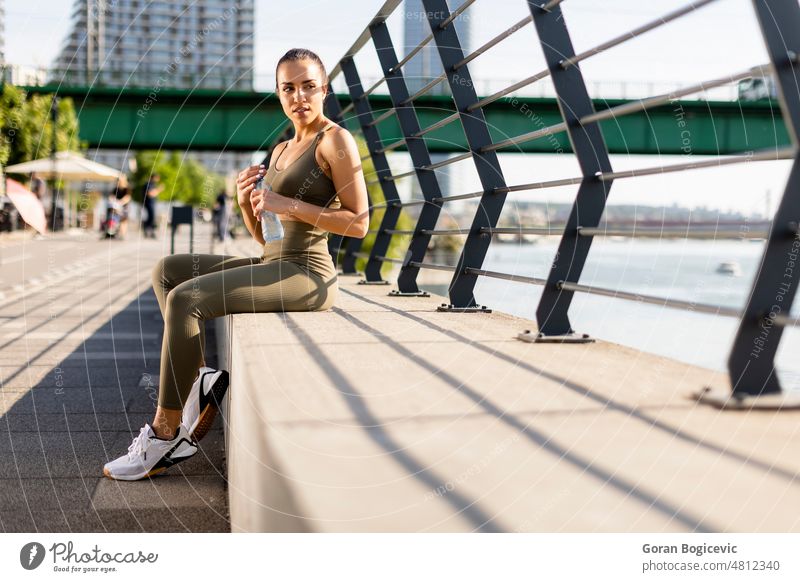 Young woman taking a break during exercise on the river promenade active adult arab athlete athletic beauty closeup drink drinking female fit fitness having