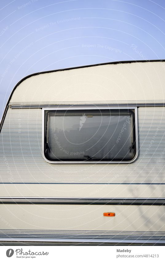 Window with sunscreen of an old caravan in pastel shades and natural colors for camping and vanlife in the sunshine at the campsite at the glider airfield in Oerlinghausen near Bielefeld on the Hermannsweg in the Teutoburg Forest in East Westphalia Lippe