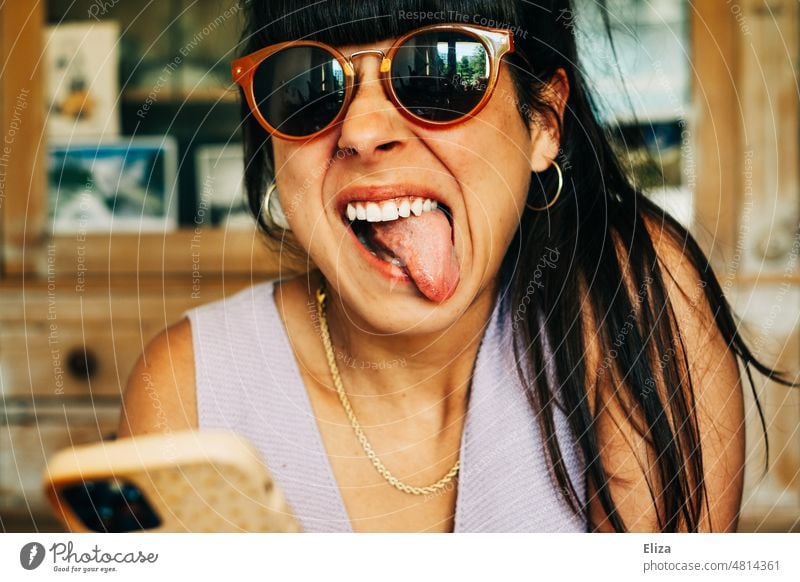 Woman with sunglasses makes funny grimace and sticks out her tongue Sunglasses Tongue out Grimace Brash bunkum Face portrait Funny Stick out Facial expression