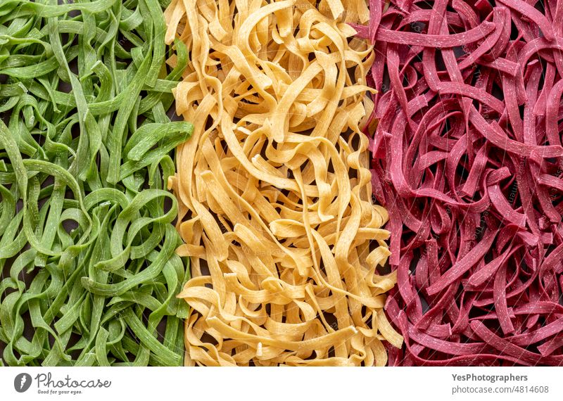 Uncooked pasta above view, close-up. Tricolor pasta arranged as the italian flag abstract backdrop background beet carbs classic cuisine delicious details dry