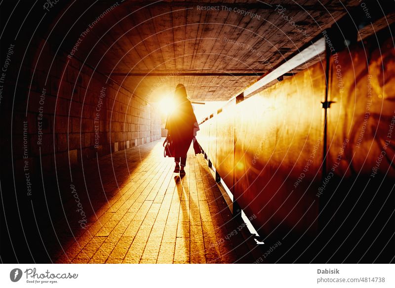 Woman silhouette at tunnel with sun rays woman sunset lonely shadow summer dark city street walk road lifestyle tourism evening vacation back girl light young