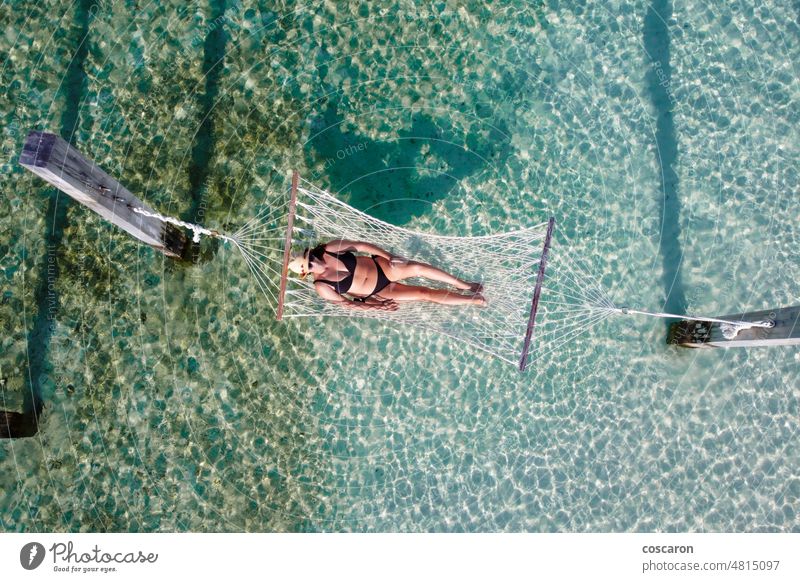 Attractive woman relaxing on a hammock over the water. Air view. above aerial air bay beach bikini blue calm drone drone photo enjoy exotic holiday idyllic