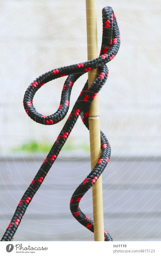 black red barrier rope twists waywardly around bamboo pole Bamboo stick perpendicular Barrier rope sold by the metre Slings Rotations Rope Rubber String Band