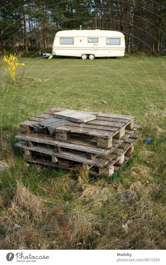 Stacked wooden euro pallets on green lawn in spring with caravans for camping and vanlife on the campsite at the glider airfield Oerlinghausen near Bielefeld in the Teutoburg Forest in East Westphalia Lippe