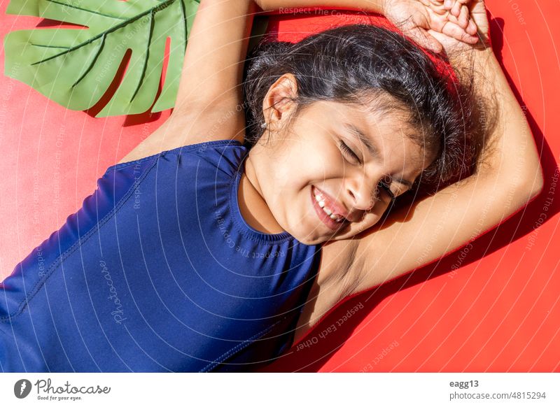 Little girl with a swimsuit is receiving the sun with direct light. child portrait sunbathing lemonade drinking facial expression swimwear pool lying down