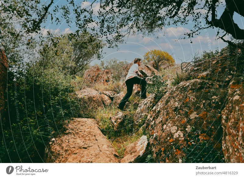 Woman in black hiking pants climbing rocky hiking trail in Sardinia path Hiking Ascending Go up ascent trees bushes Landscape Nature mountains Athletic Mountain