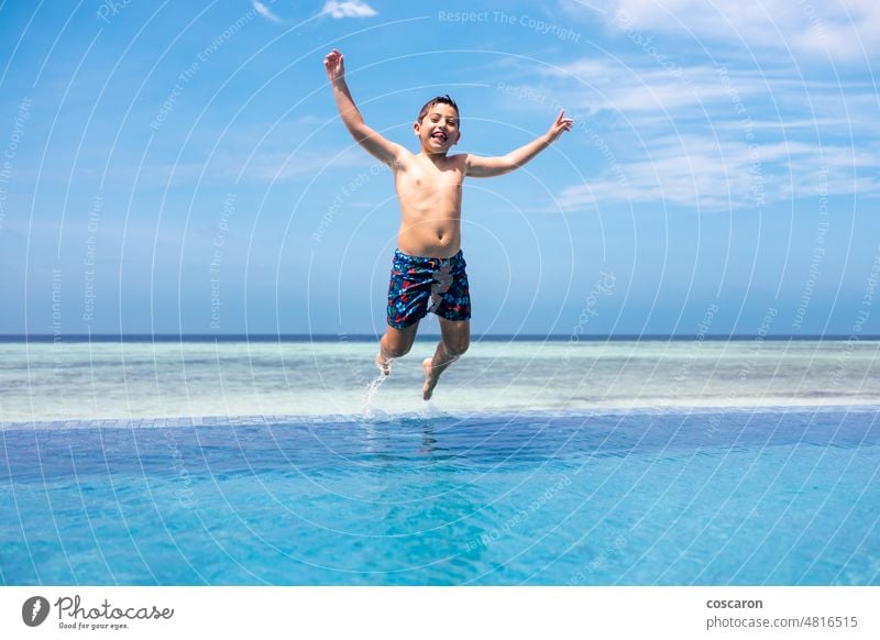 Funny kid jumping into a infinity swimming pool active baby blue blue sky boy child family fun funny happiness happy holiday hotel island joy landscape leisure