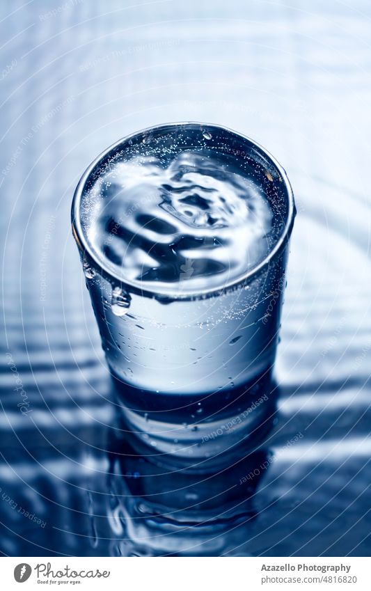 Blue monochrome image of water splashing in a glass. blue splashed ripples blur blurry wave surface droplets drink wet aqua dark black shiny motion minimalism