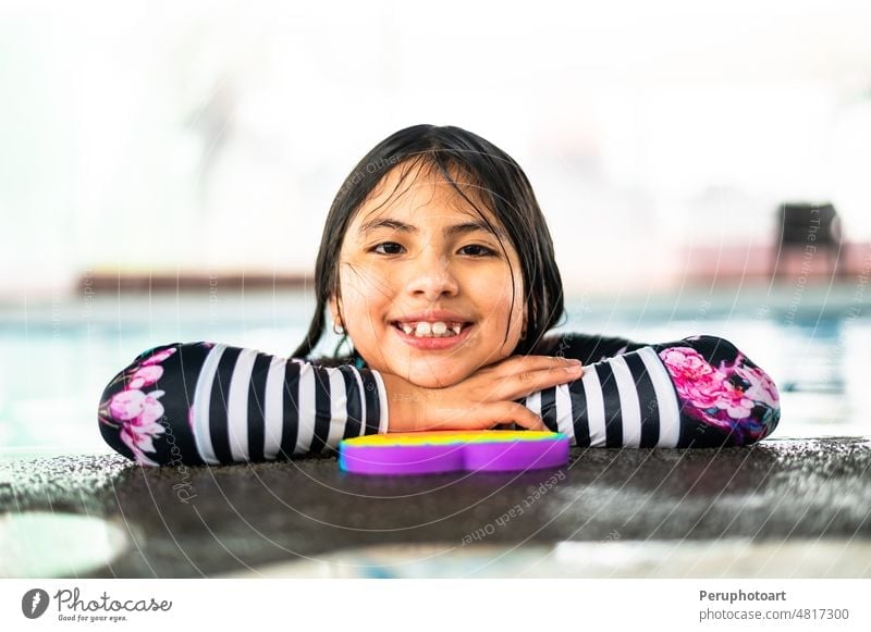 Portrait girl having fun in indoor swimming-pool. The girl is resting at the water park. Active happy kid. Swimming school for small children. Concept friendly family sport and summer vacation.