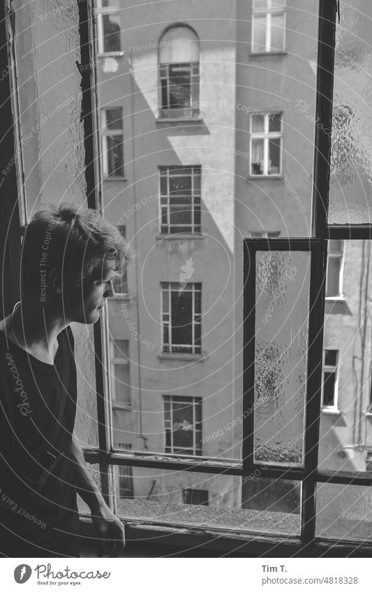 a young man looks thoughtfully out of the stairwell window into the courtyard of an old Berlin backyard Man Window Prenzlauer Berg Staircase (Hallway) b/w