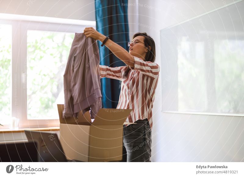 Woman unpacking a purchased package of clothes domestic life confidence woman indoors home house people young adult casual female Caucasian attractive beautiful