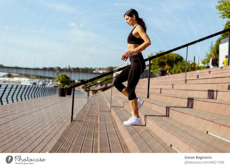 Young woman in sportswear exercising on a river promenade active athletic beautiful caucasian energy exercise female fit fitness flexibility healthy jogger