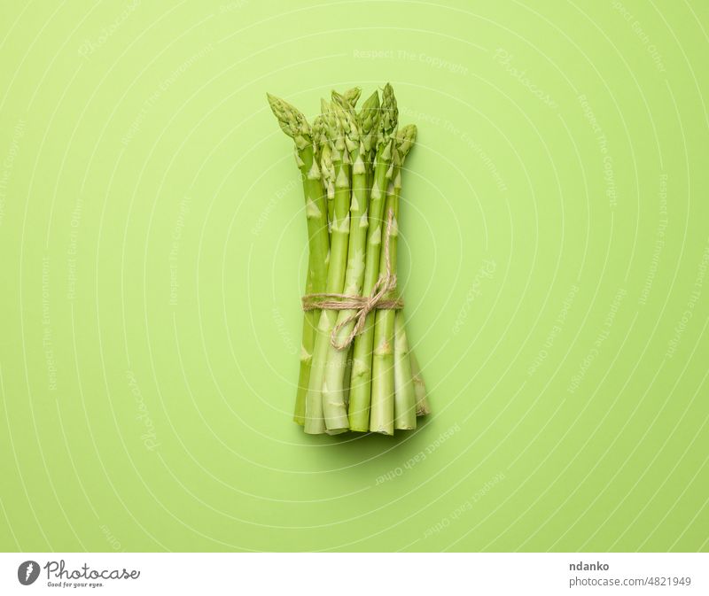 bunch of fresh raw asparagus on green paper background, top view ingredient food vegetable vegetarian organic diet healthy natural epicure cooking season
