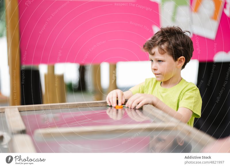 Adorable child standing at table in entertainment club air hockey game concentrate boy play amusement childhood center portrait adorable focus spend time