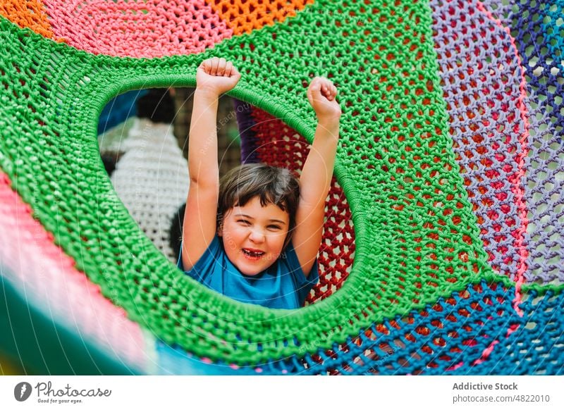 Happy cute child lying inside of colorful hammock girl relax park happy enjoy smile knitted carefree portrait raised arms adorable content glad positive kid