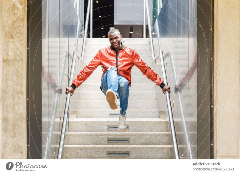 Positive trendy black guy jumping on stairs on street man staircase smile positive happy active trick railing city male young african american ethnic cheerful