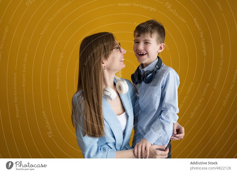 Mom with headphones in neck embracing son mother music listen glad together home woman boy meloman happy wireless cheerful child kid tune parent smile love mom