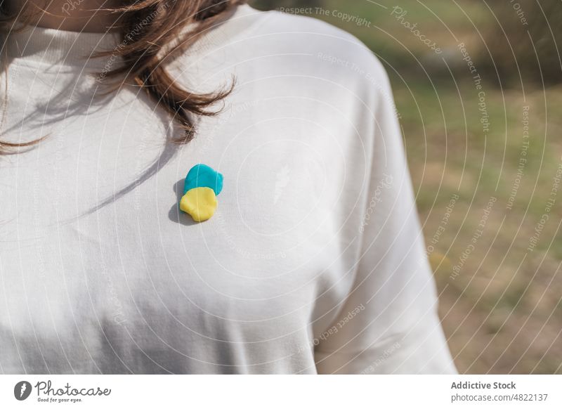 Crop anonymous woman with Ukrainian flag brooch on t shirt ukrainian peace symbol patriot national meadow countryside feminine independent yellow blue color