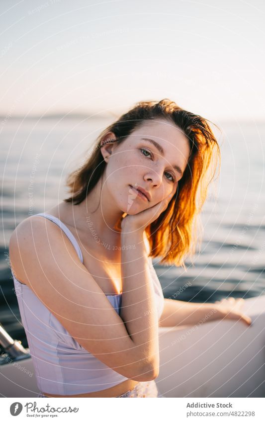 Peaceful lady touching face while relaxing on sailboat woman cruise sea touch face sunset yacht trip tourist feminine vacation female young brown hair