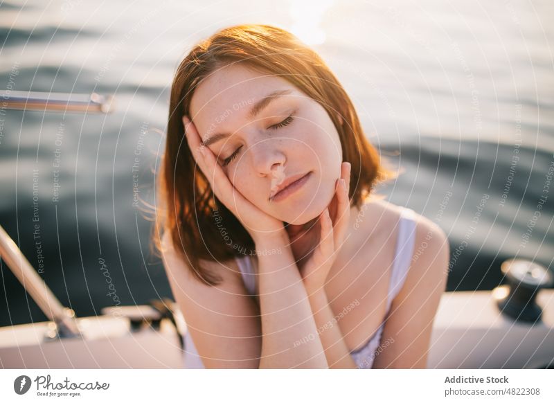 Peaceful lady touching face while relaxing on sailboat with closed eyes woman cruise sea eyes closed touch face sunset yacht trip tourist feminine vacation