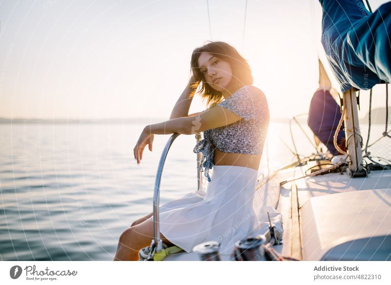 Stylish female tourist resting on yacht and admiring sunset over sea woman admire sailboat traveler vacation cruise holiday style portrait trendy trip young