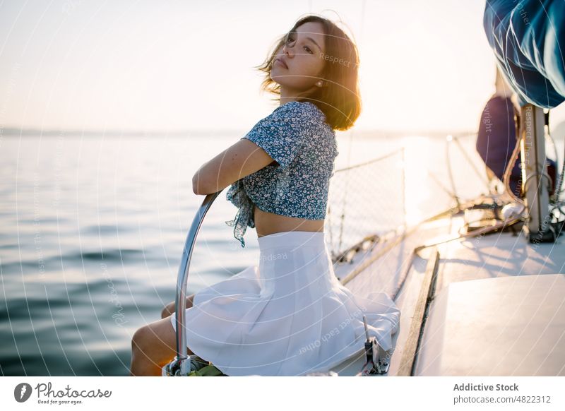 Stylish female tourist resting on yacht and admiring sunset over sea woman admire sailboat traveler vacation cruise holiday style portrait trendy trip young